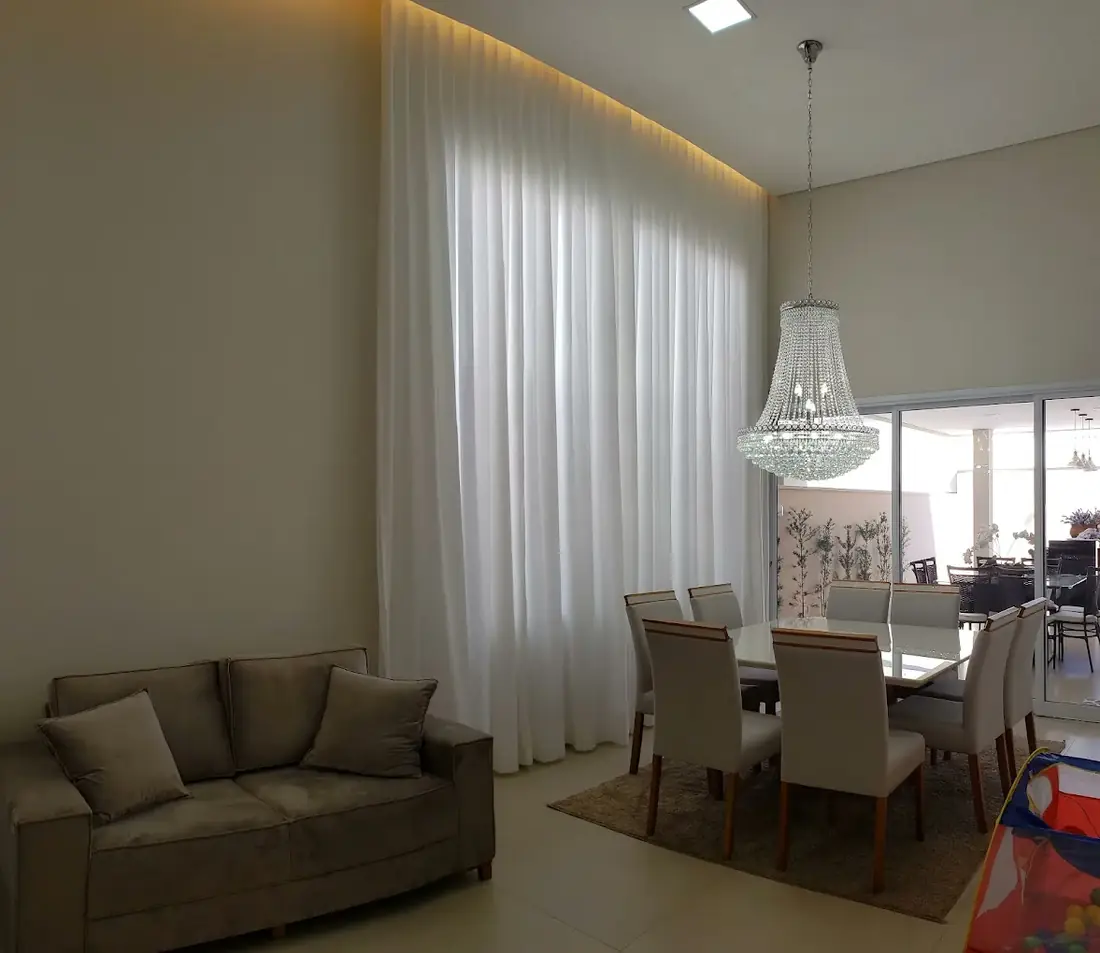 Sala de jantar com cortina sob medida e lustre